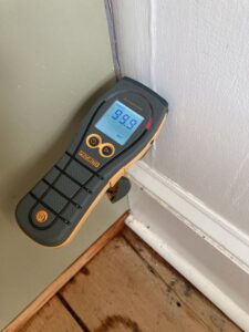 A moisture meter showing 99.9% wet on a wall, indicating severe water damage, used by CleanBright Surface Restoration in Latham, NY.