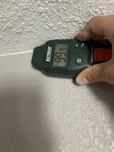A moisture meter showing a 6.6% reading on a wall, indicating moisture assessment by Roeun's Restoration and Cleaning LLC in Rochester, MN.