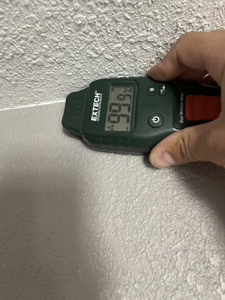 A moisture meter showing a 6.6% reading on a wall, indicating moisture assessment by Roeun's Restoration and Cleaning LLC in Rochester, MN.
