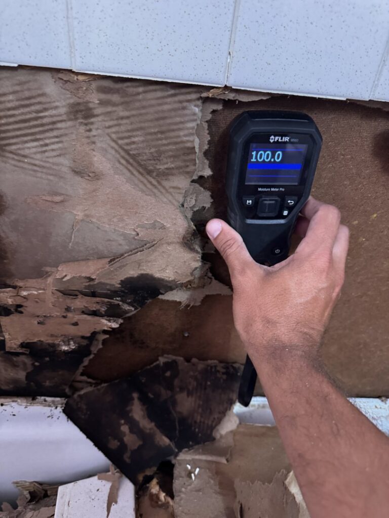 A moisture meter showing a high reading on a severely water-damaged wall during assessment by RestoPros in Bangor, ME.