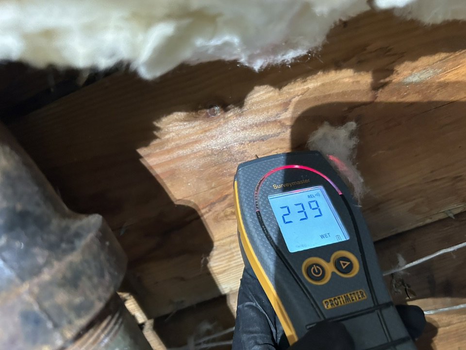 A moisture meter showing a 'WET' reading on a wooden beam, indicating water damage, used by Utah Flood Guys in Sandy, UT.