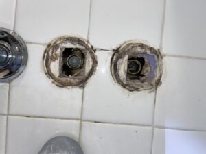 Mold and water damage visible around shower valve openings, indicating a leak repair and restoration by Hull Plumbing, Inc. in Oklahoma City, OK.