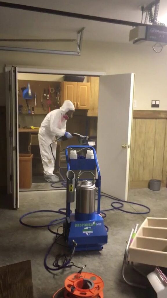A Restored Air specialist in PPE performing mold remediation fogging in a garage in Summerville, SC.