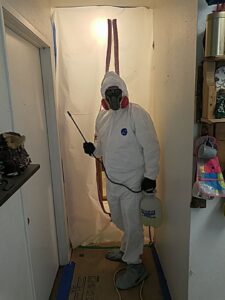 A mold remediation specialist in a hazmat suit spraying in a contained area for North Shore Restore in Duluth, MN
