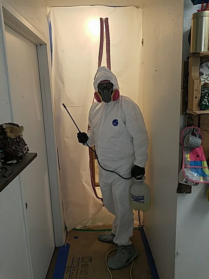 A mold remediation specialist in a hazmat suit spraying in a contained area for North Shore Restore in Duluth, MN