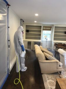 A Green Home Solutions specialist spraying during mold remediation with containment barriers in Mount Airy, MD.