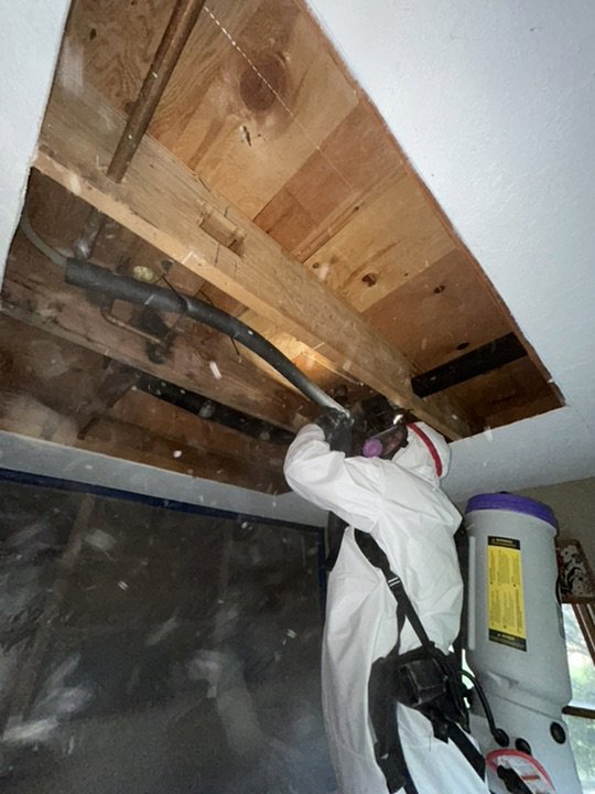 A worker in a hazmat suit performing mold remediation on an exposed ceiling for Utah Home Restoration in Springville, UT