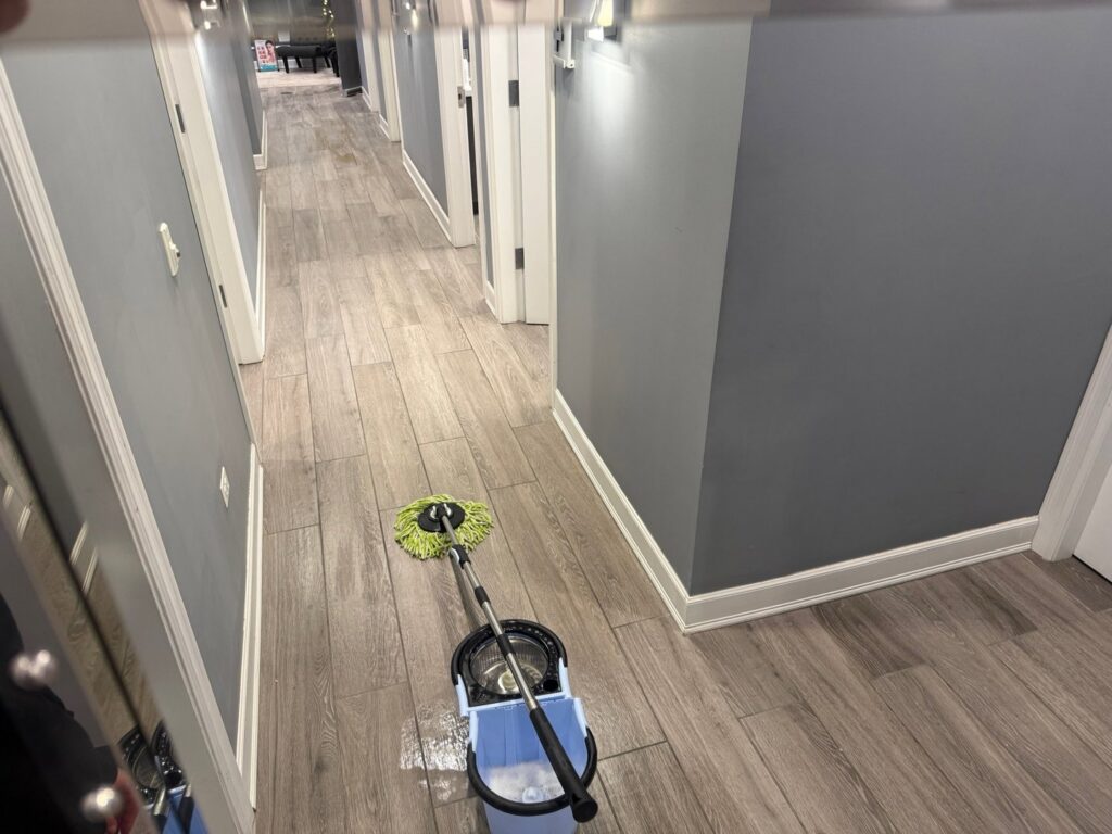 A mop and bucket ready for use in a hallway, representing the active cleaning services by Messy To Clean in Aurora, IL.