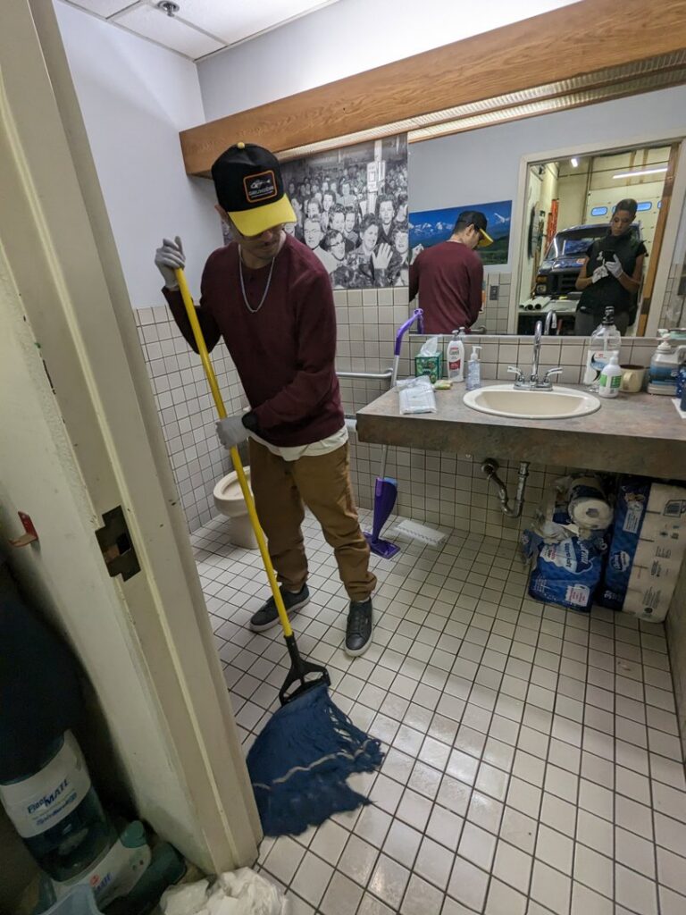 A professional cleaner from Leave The Dust To Me Cleaning Services LLC in Anchorage, AK, mopping a tiled restroom floor.