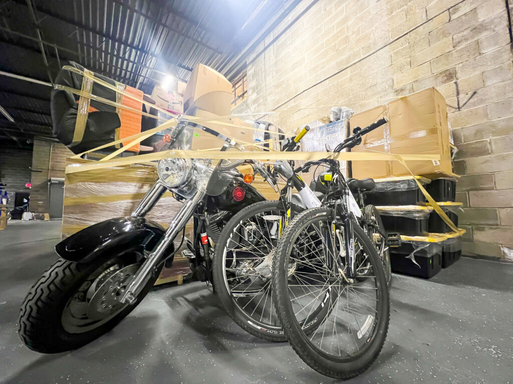 A motorcycle and bicycles are securely wrapped and stored, indicating moving or storage services by J.Gentle Van Lines in Elizabeth, NJ.