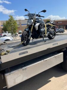 A motorcycle securely strapped onto a flatbed tow truck from Jay Towing Services in Houston, TX.