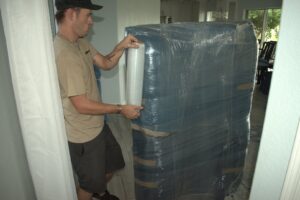 A professional mover applying plastic wrap to furniture for protection by Moving Pros LLC in Surprise, AZ.