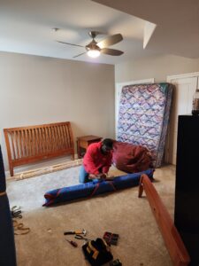 A professional mover from Joy Haul Professional Movers assembling a bed frame in a bedroom in Columbia City, IN.