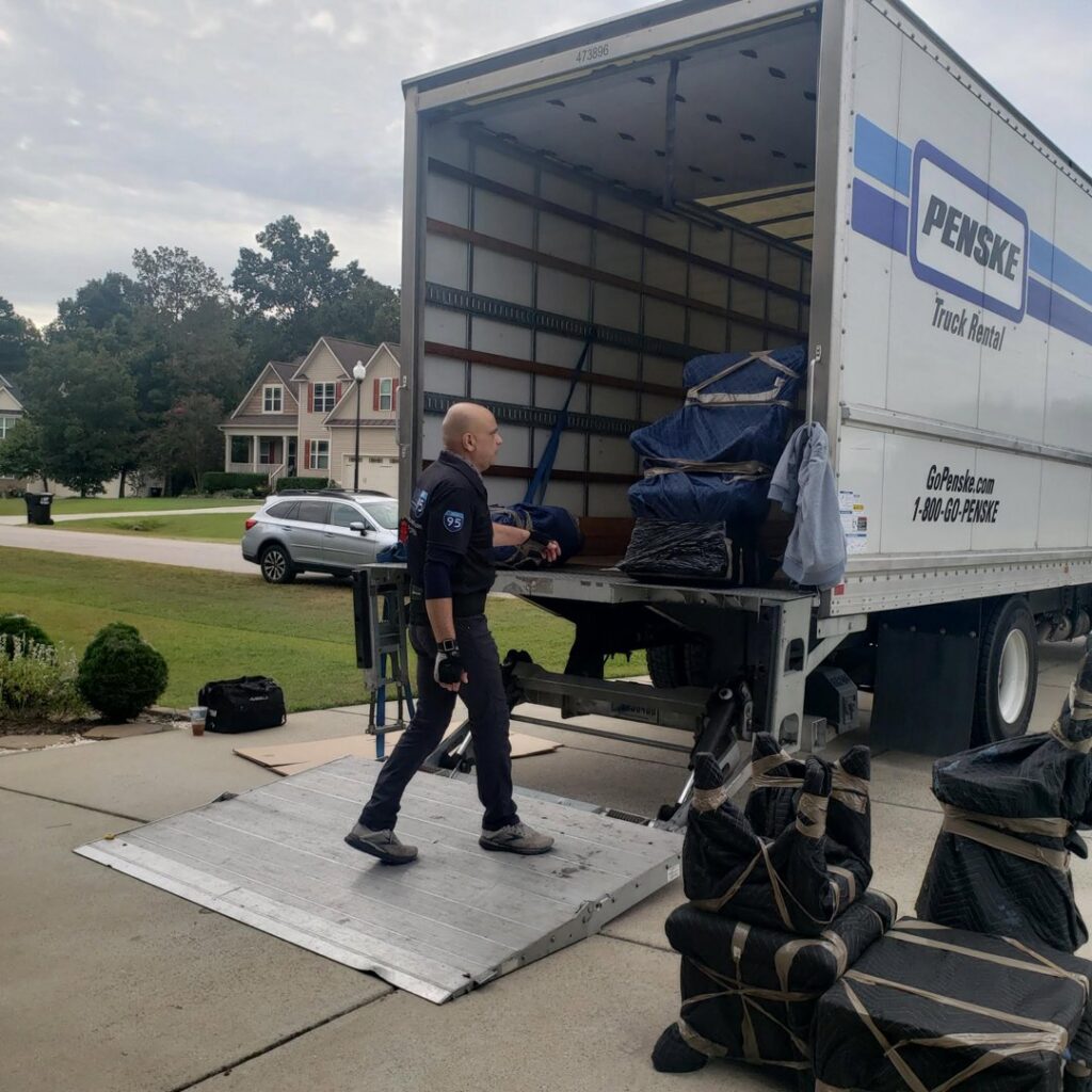 A mover carrying a box through a room with packed items for Household Goods Moving and Storage in Rockville, MD