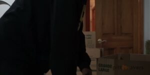 A mover carrying a box inside a home, with a PittMovers branded box in the foreground in McKees Rocks, PA