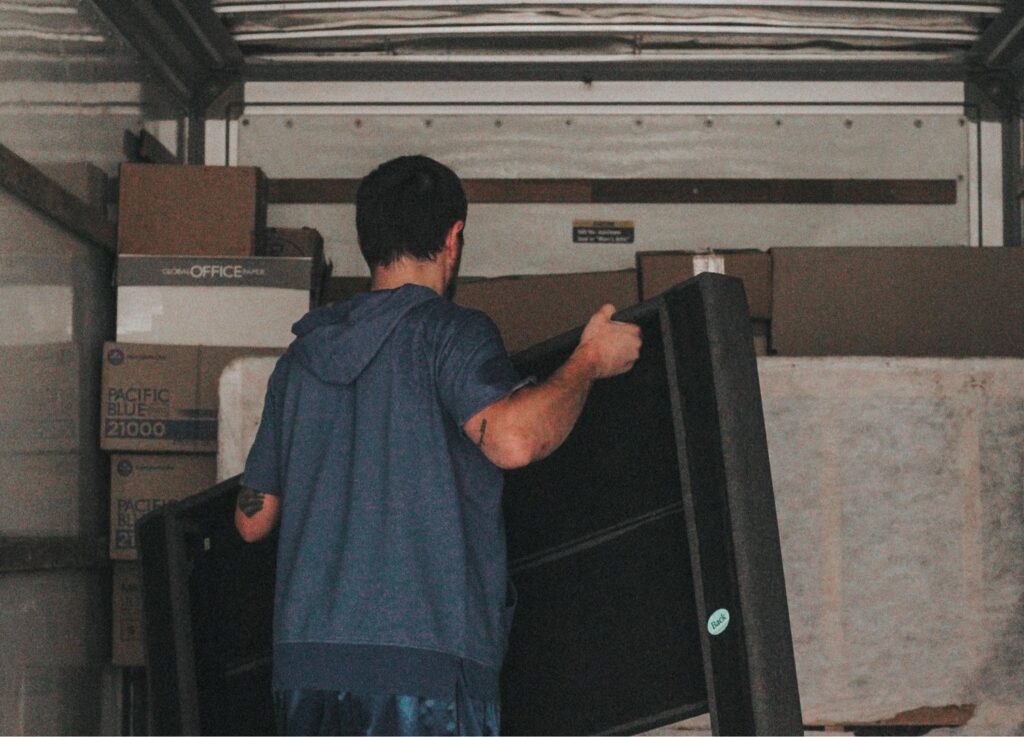 An Ingenuity Moving team member carrying a large item into a moving truck in Kansas City, MO.