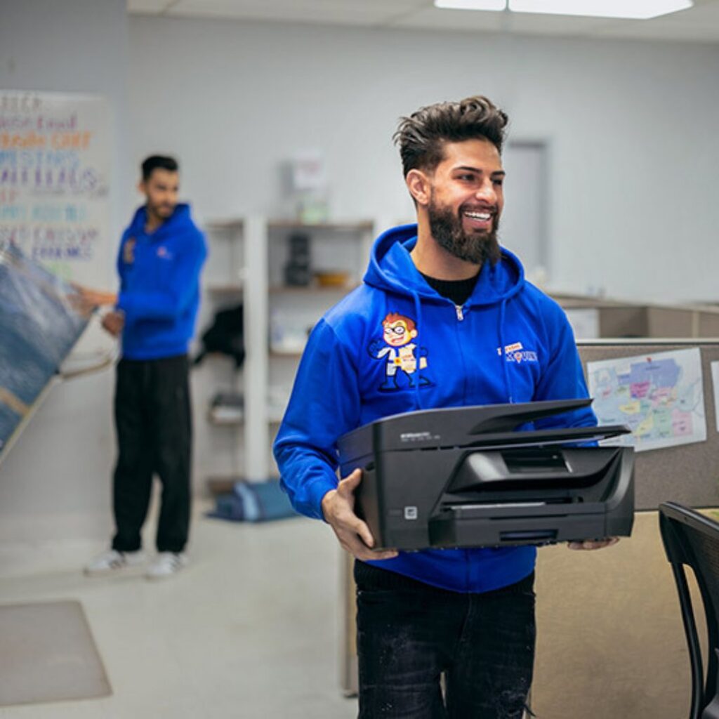 A mover from Let's Get Moving carrying a printer during an office relocation in Saint Petersburg, FL.