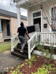 A mover carefully carrying a sofa into a house for ASAP Elite Hauling and Delivery in New Orleans, LA.