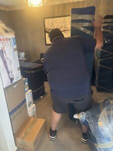 An Advantage Express Movers team member carrying wrapped furniture inside a home during a move in Arlington, TX.