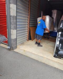 A Ron's Moving team member carrying a wrapped sofa into a storage unit in Little Rock, AR.