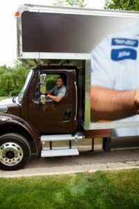 A smiling mover from Leaders Moving & Storage Co. driving a branded moving truck in Indianapolis, IN.