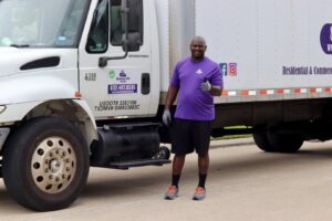 A friendly mover from Kingdom Men Movers in Houston, TX, giving a thumbs up next to a large moving truck.
