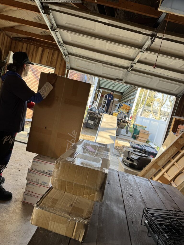 A Top Notch Movers employee handling boxes in a garage with a moving truck visible in the background in Lauderhill, FL.