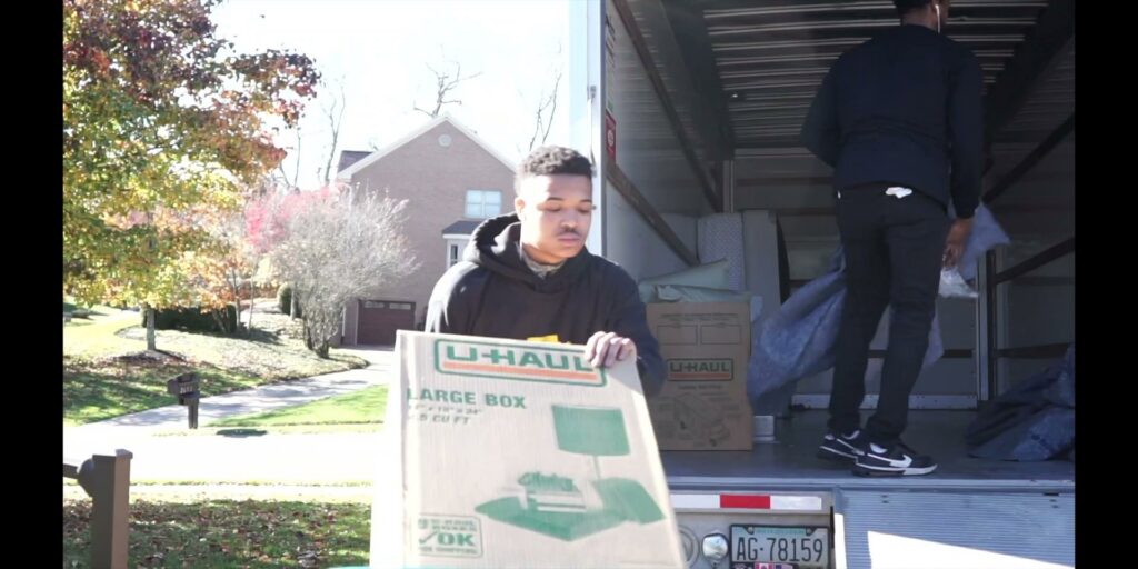 A PittMovers team member holding a U-Haul box at the back of a moving truck in McKees Rocks, PA