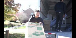 A PittMovers team member holding a U-Haul box at the back of a moving truck in McKees Rocks, PA