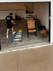 A professional mover from Next Step Moving in a garage with furniture and a ladder, preparing for a move in Eau Claire, WI.