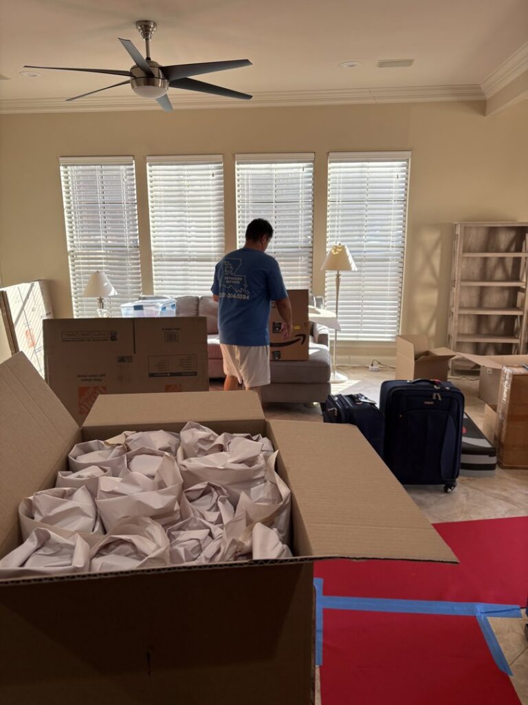 A mover from Reynolds Moving in Baton Rouge, LA, standing in a room with packed boxes and luggage, ready for transport