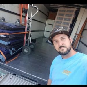 A mover from Rising Phoenix Movers LLC standing inside a moving truck with blankets and a hand truck in Phoenix, AZ.