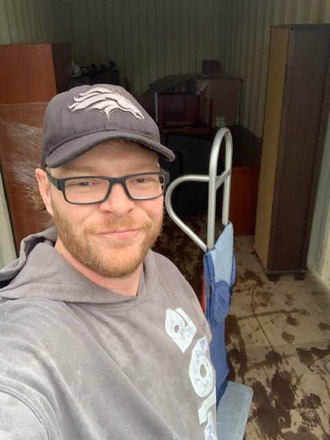 A friendly mover standing inside a moving truck with furniture and a hand truck at Able Movers in Hillsboro, OR.