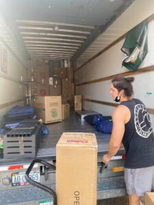 A mover from Gifted Hands Moving & Storage in Collierville, TN, pushing a box on a dolly into a packed moving truck.