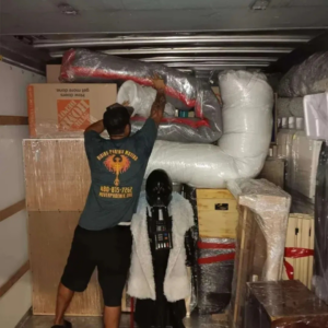 A mover from Rising Phoenix Movers LLC carefully loading items into a moving truck in Phoenix, AZ.