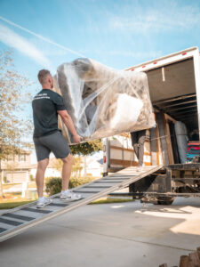 A mover from The Local Movers loading a large, wrapped furniture item onto a moving truck in Orlando, FL.