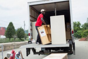A PittMovers team member loading a wooden shelf onto a moving truck using a ramp in McKees Rocks, PA