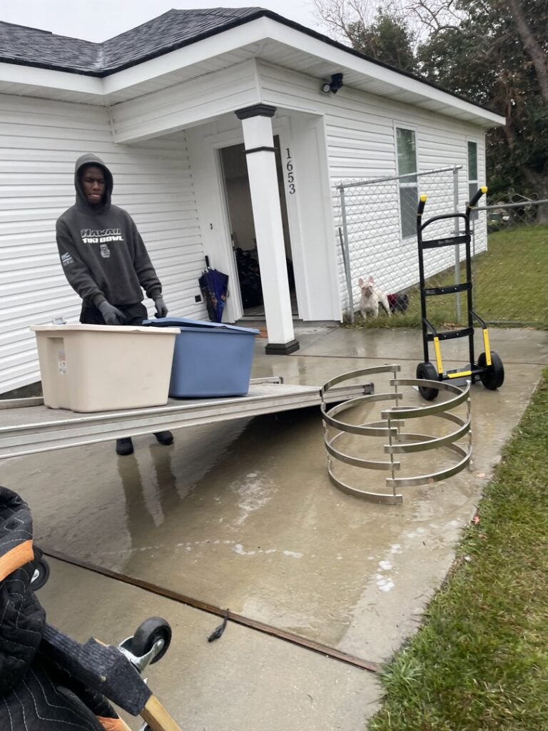 A mover using a ramp to load storage bins onto a truck for ASAP Elite Hauling and Delivery in New Orleans, LA.