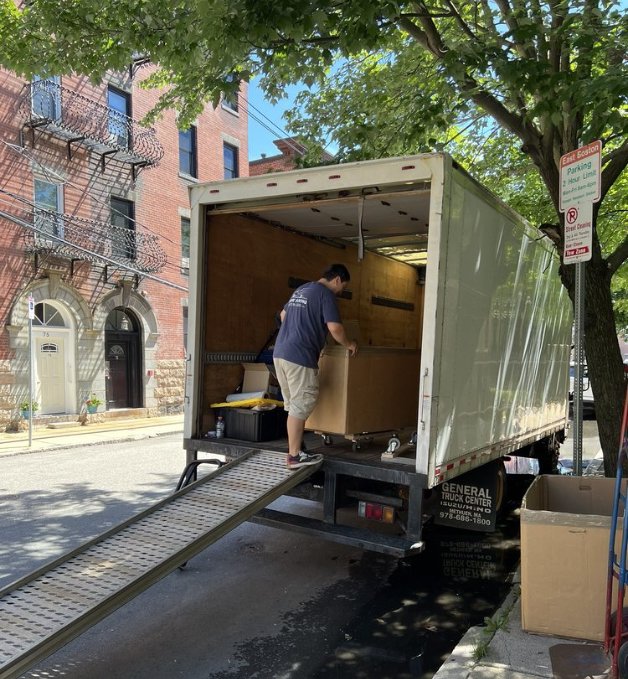 A Prime Moving professional loading a box onto a moving truck using a ramp in Boston, MA.