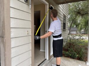 A mover from The Local Movers measuring a doorway with a tape measure to ensure furniture clearance in Orlando, FL.
