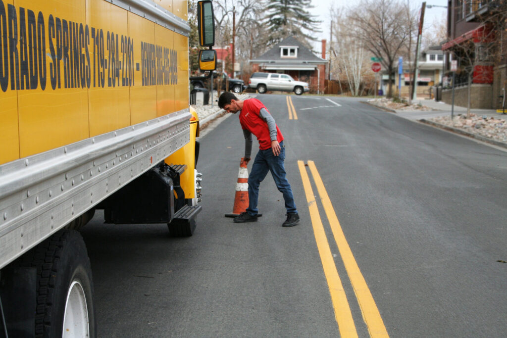 A mover placing a safety cone behind a moving truck for Fatboy Slims Moving Company in Colorado Springs, CO.