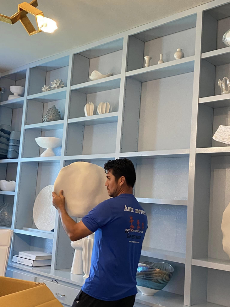 A professional mover from Antz Movers Company in Austin, TX, carefully preparing a fragile white vase for packing.