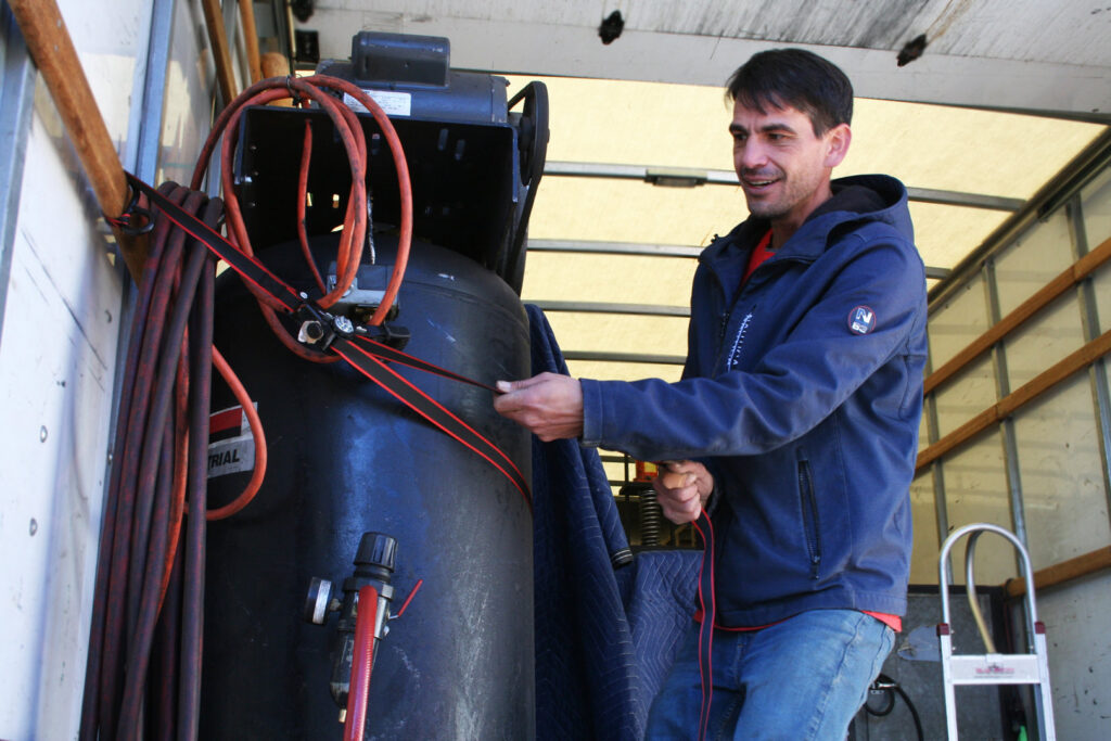 A mover securing heavy equipment with straps inside a moving truck for Fatboy Slims Moving Company in Colorado Springs, CO.