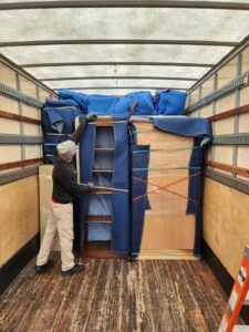 A professional mover from Joy Haul Professional Movers carefully securing wrapped furniture inside a moving truck in Columbia City, IN.
