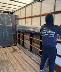 A Prime Moving professional securing furniture with straps and blankets inside a moving truck in Boston, MA.