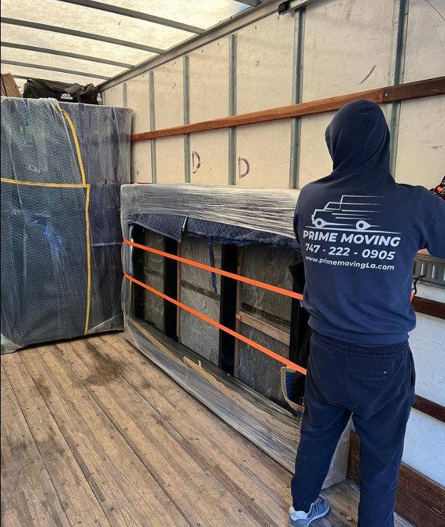 A Prime Moving professional securing furniture with straps and blankets inside a moving truck in Boston, MA.