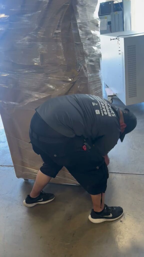 An Advantage Express Movers team member securing a large, wrapped item on a pallet in Arlington, TX.