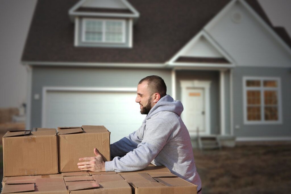 A PittMovers team member stacking moving boxes outside a house in McKees Rocks, PA