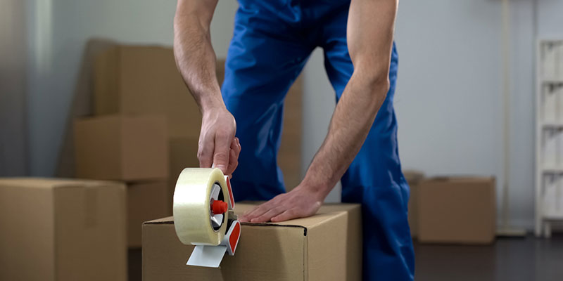 A professional mover taping a cardboard box for packing at All Around Town Movers in Memphis, TN.