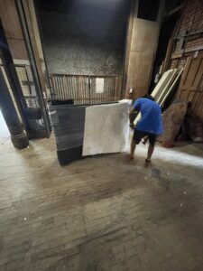 An Ingenuity Moving team member transporting wrapped furniture on a dolly in Kansas City, MO.